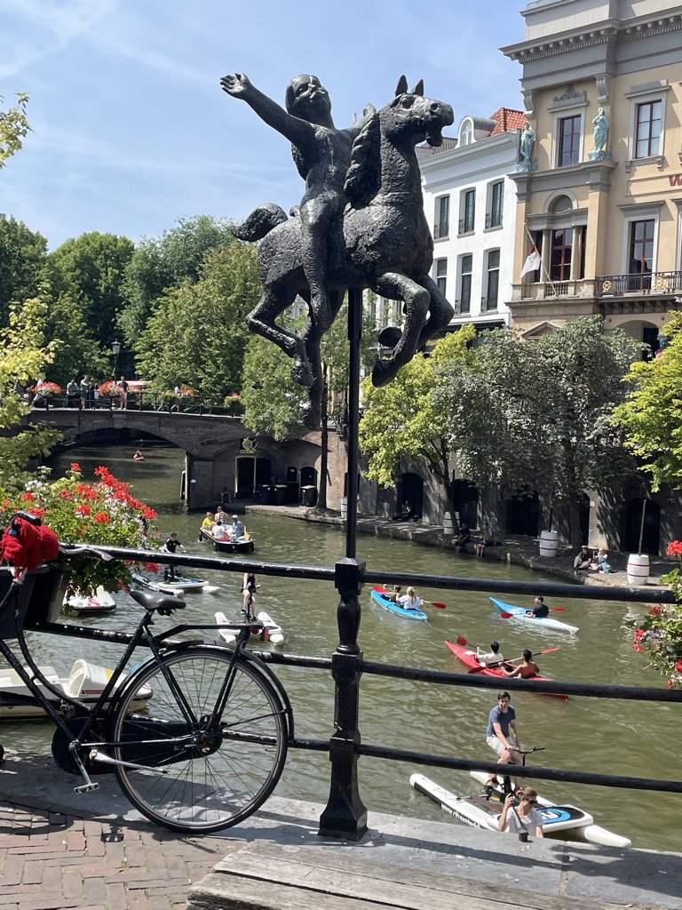 A bicycle on a canal bridge in Utrecht, with kayakers and paddleboarders on the water below